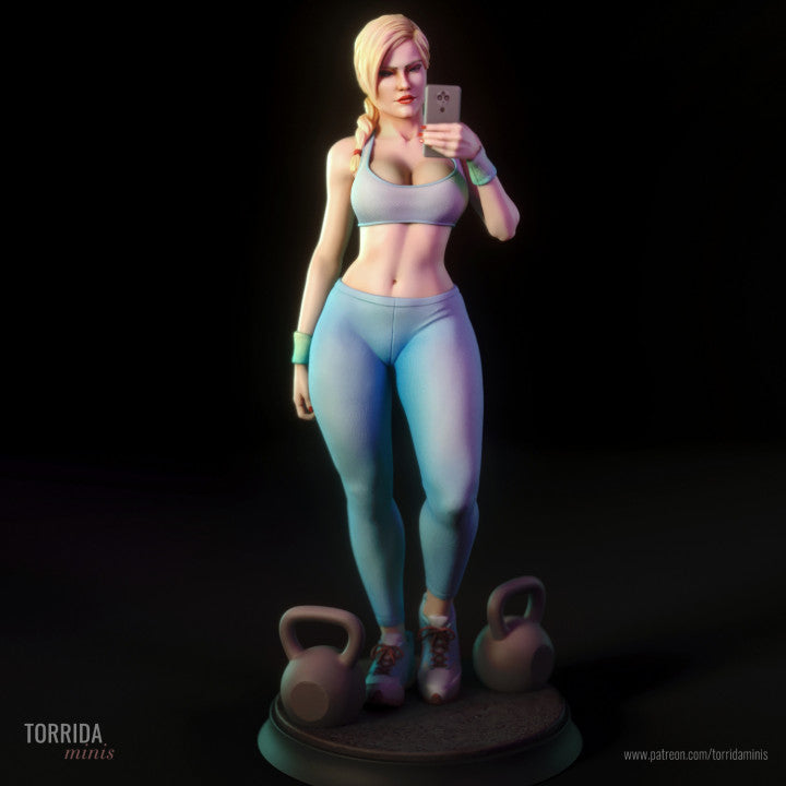 Miniature female gym figure standing upright on a round base with kettlebells, posed mid-selfie. Athletic outfit with sports bra and leggings. Braided hair and confident expression. Stylised 1/10 scale resin model designed for boutique collectors and painters.