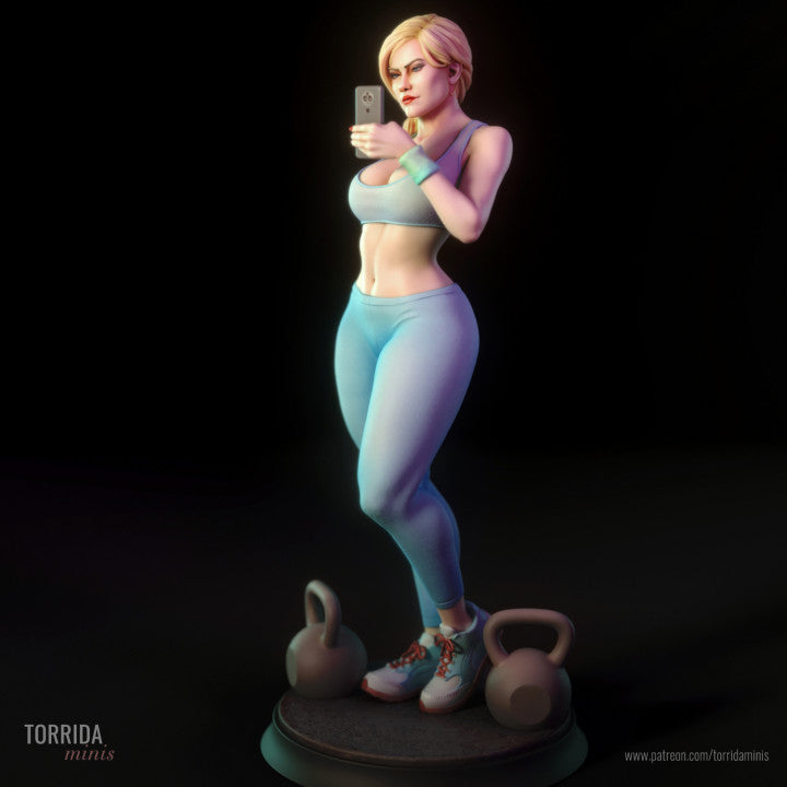 Side view of gym-themed resin mini figure taking a selfie. Character features a toned physique, detailed sportswear, and expressive pose. Positioned between kettlebells on a display base. Premium 1/10 scale collectible for adult miniature enthusiasts.
