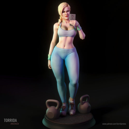 Miniature female gym figure standing upright on a round base with kettlebells, posed mid-selfie. Athletic outfit with sports bra and leggings. Braided hair and confident expression. Stylised 1/10 scale resin model designed for boutique collectors and painters.